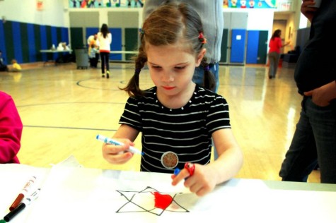 A young girl puts thought into her matzoh cover design. Photo from SmallCity@Senesh; courtesy The Covenant Foundation