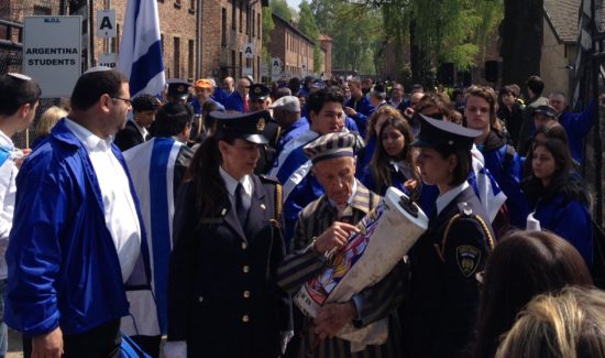 Holocaust survivor Edward Mosberg (in front, center) gives a history lesson about a Torah scroll that also survived the Holocaust era. The Torah dates back to the late 17th or early 18th century, according to a DNA test conducted at the University of Arizona. Photo credit: Jacob Kamaras.