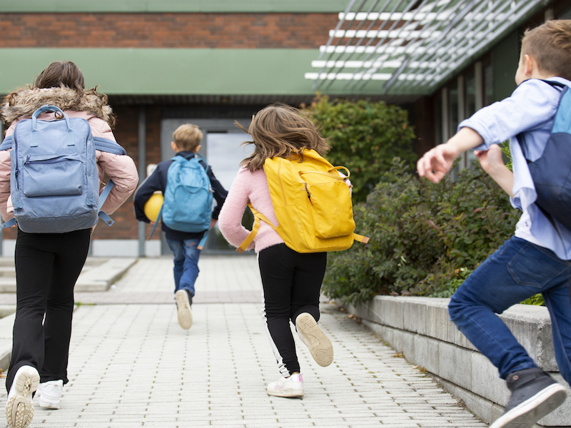 Rear view of schoolchildren running