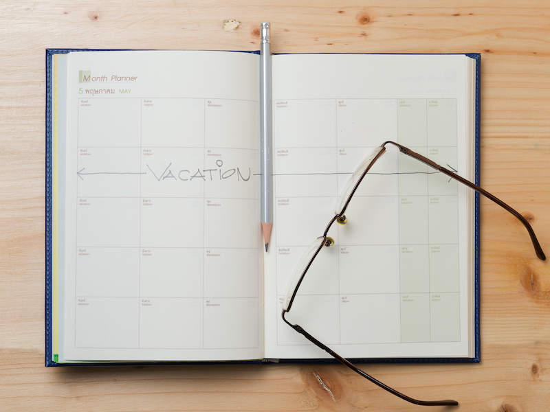 Vacation plan written on calendar by a pencil on wood background