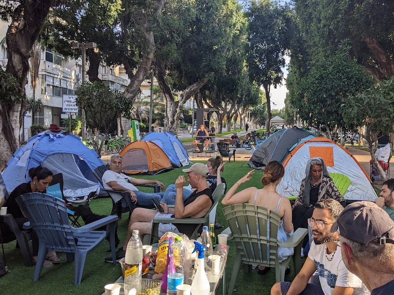 Activists sit amid tents on Rothschild Boulevard in Tel Aviv on June 21, 2022.