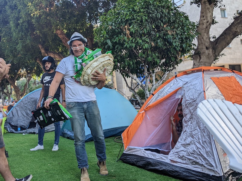 A man stands with food amid the tents.