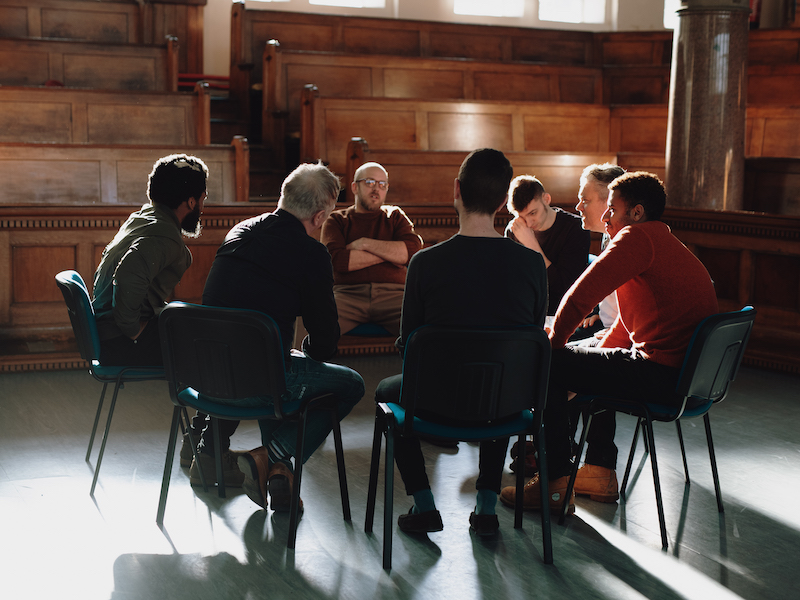 A group of men sit in a circle.