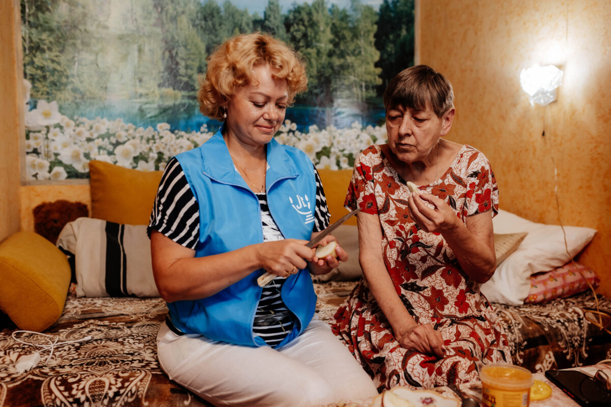 An unnamed American Jewish Joint Distribution Committee worker gives an apple and honey to Zoya Nagorskaya, a 69-year-old retired kindergarten teacher from Poltava, Ukraine, ahead of Rosh Hashanah in 2023.