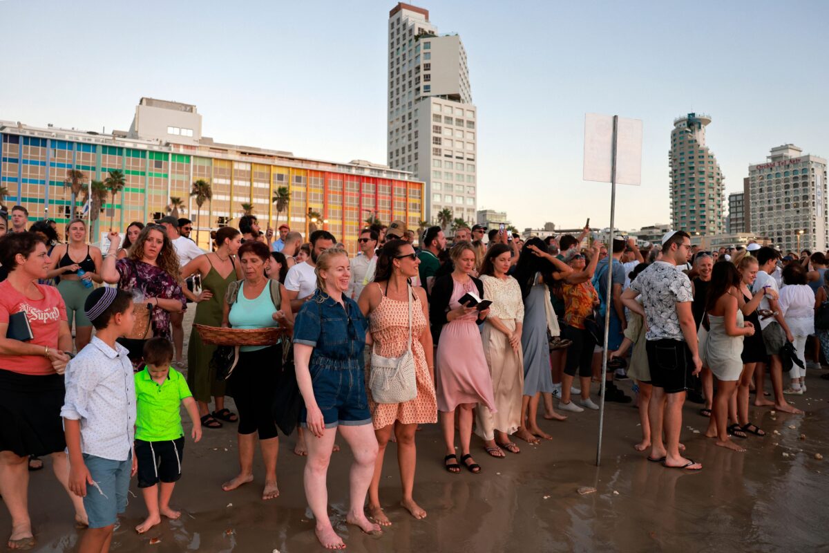 People stand along the Mediterranean sea shore as religious Jews gather to perform the Tashlich ritual in Tel Aviv on September 17, 2023 during which "sins of the past year are cast into the water to the fish", on the second day of "Rosh Hashanah", the Jewish new year, ahead of "Yom Kippur" or the Day of Atonement.