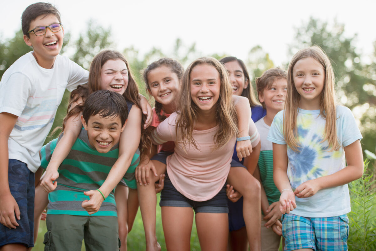 Smiling children standing together outside in the summer